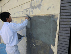 ライオンホームの塀塗装リフォーム。塗料を除去した後の壁に、カチオンというセメントで補修しているところです。