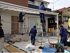 長岡京市のエクステリア工事。次にガレージにカーポートを取り付けます。シルバーの枠組を職人が組み立てているところです。