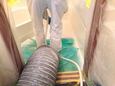 西京区のお風呂浴室リフォーム。下地を整える為に研磨すると粉が出るので、それをダクトホースのような物で吸って外へ出しています。