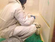 西京区のお風呂浴室リフォーム。職人さんが防護服を着て塗装中です。