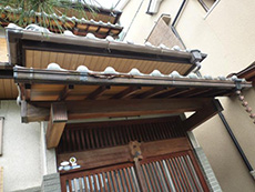 長岡京市の玄関リフォーム。リフォーム前の木製引き戸です。引き戸上のひさしの雨樋も傷んでいました。