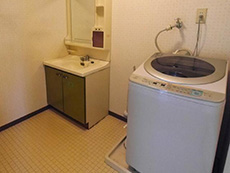 大山崎町のマンションリフォーム。リフォーム前の洗面所です。洗面化粧台と洗濯機が置いてあります。